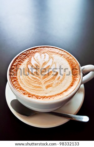 Cup of latte coffee with leaf shape art on foam