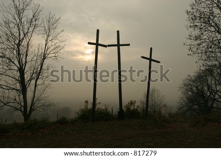 Three wooden crosses sitting on a hill.