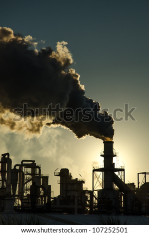 Smoking chimney  at sunset on industrial buildings complex.
