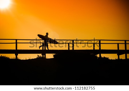 A surfer running to the beach at sunset in Portugal.