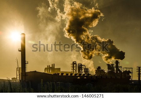 Air pollution coming from factory smoke stacks over sunset. Global concept earth preserving. Halt global warming