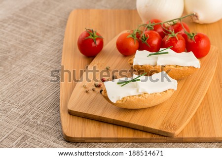 Closeup detail of bread with cottage and tomato over wood board tray.