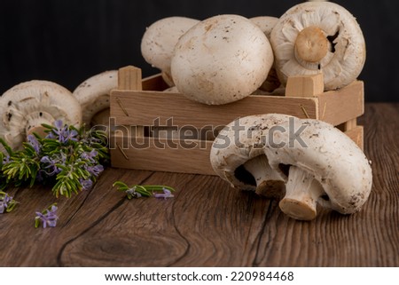 Champignons in a wooden box on dark boards.