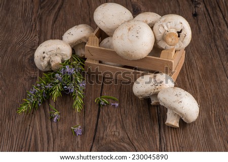 Champignons in a wooden box on dark boards.