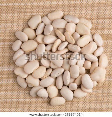 Top view of circle of white beans against beige vinyl background.
