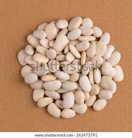 Top view of circle of white beans against brown vinyl background.