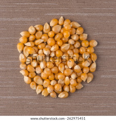 Top view of circle of corn against beige vinyl background.