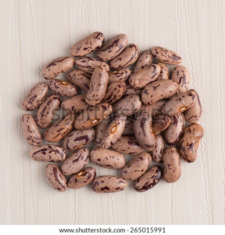 Top view of circle of pinto beans against beige vinyl background.