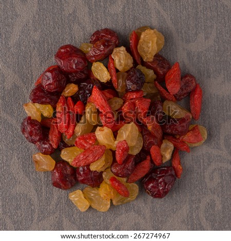 Top view of circle of mixed dried fruits against beige vinyl background.