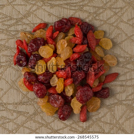 Top view of circle of mixed dried fruits against green vinyl background.