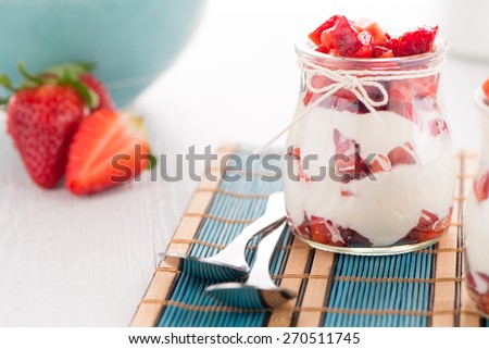 Strawberries desert with cream served on glass cups over table top.