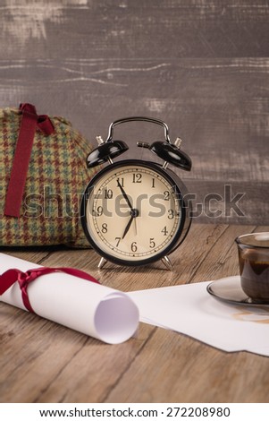 Old clock, hat coffee and paper sheets on old Wooden table.
