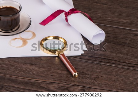 Wrapped paper sheets and magnifying glass on Old Wooden table.