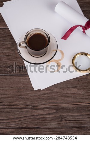 Coffee cup, paper sheets and detective hat on old Wooden table.