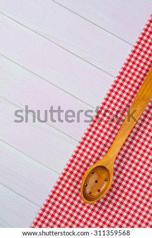 Kitchenware on white and red towel over wooden kitchen table. View from above.
