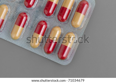 Blister pack of yellow and red pills isolated on grey background.
