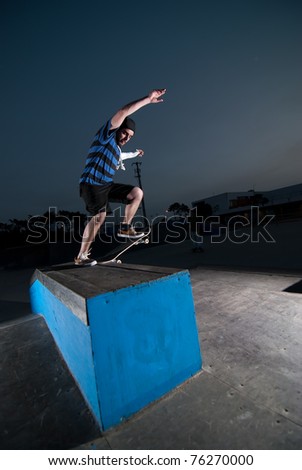 Skateboarder on a slide at night at the local skatepark.