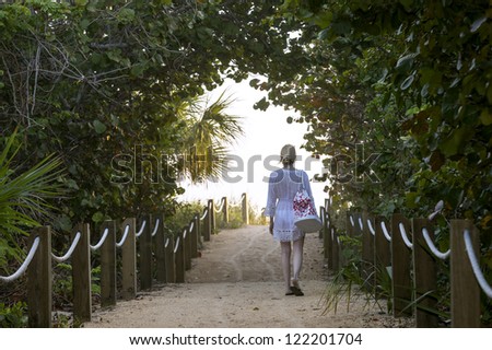 young female walking to the ocean front beach in the early morning