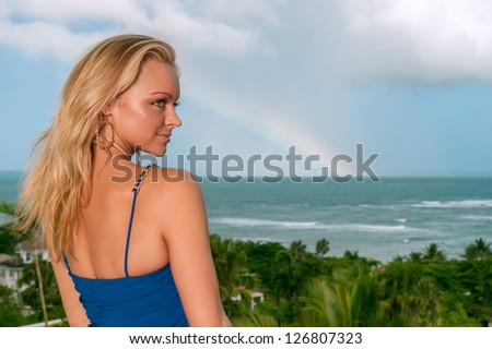 lovely female in blue dress against tropical island and ocean with rainbow