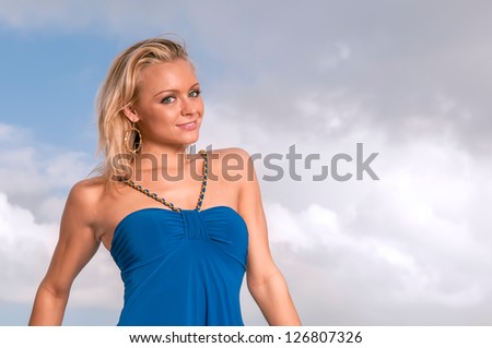 lovely female in blue dress against tropical sky and clouds