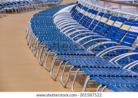 lounge chairs arranged on deck of cruise ship, focus on near chairs