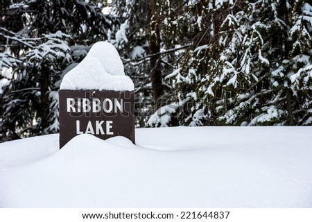 Ribbon Lake sign in winter at Yellowstone National Park with copy space in snow