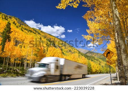 tractor trailer truck driving along Colorado highway on colorful autumn day