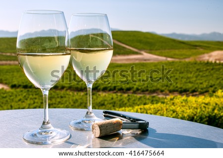 two glasses of white wine on table overlooking California wine country on sunny, cloudless day