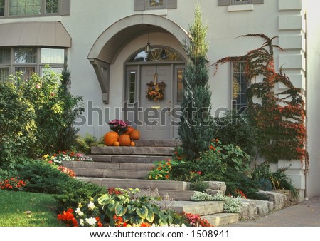 front entry of elegant home is decorated with pumpkins and fall colors