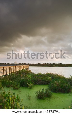 gray storm clouds over the wetland park pond and boardwalk