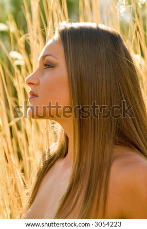 profile portrait of lovely lady in tall backlit grass