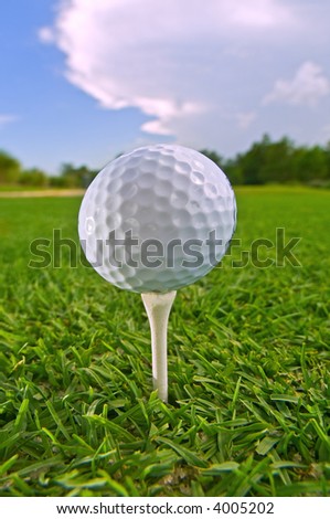golf ball on tee with sky and cloud behind