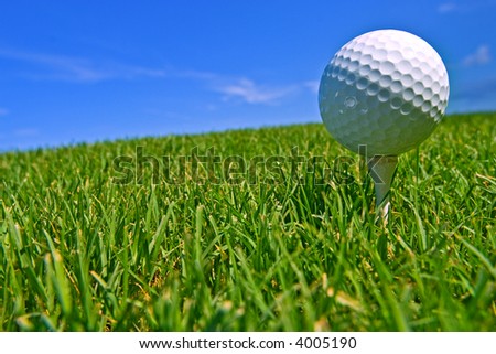 golf ball on tee with blue sky behind