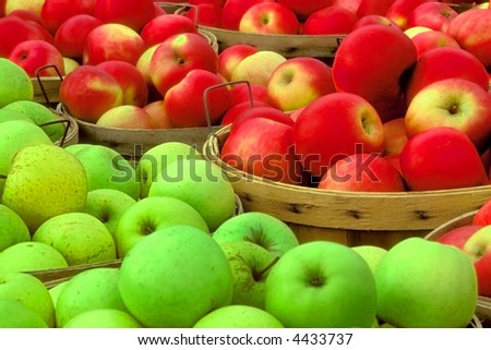 red and green apples sit in bushel baskets in fruit market