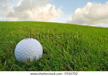 golf ball on grassy bunker with sky above