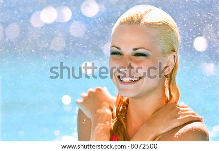 attractive blond female model in pink bikini having fun in swimming pool