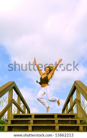 lovely blond female model jumping on stairs leading to beach