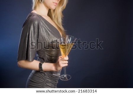 woman in party dress holding bubbling champagne against dark background with sparkle effect on champagne