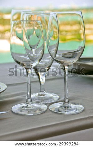 wine goblets on table setting against tropical island background
