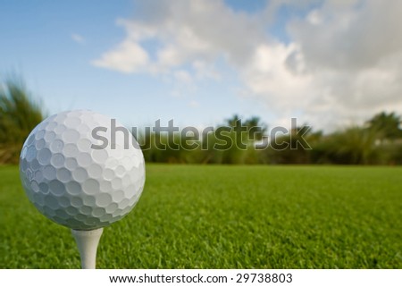 golf ball and tee on lush tropical course with copy space