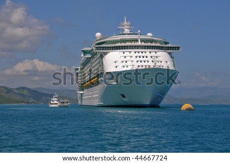 huge cruise ship anchored off coast of tropical island in Caribbean