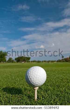 golf ball on tee with fair skies overhead