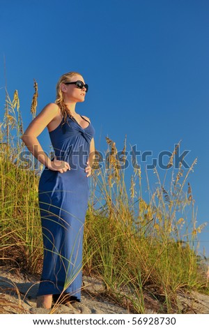 lovely blonde female model in blue dress by coastal sea oats with blue sky background