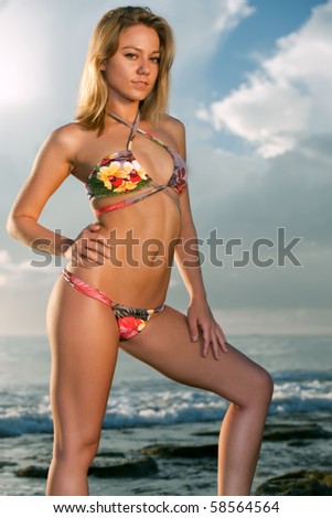 lovely female model in tropical print bikini standing at edge of atlantic ocean