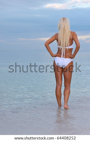 lovely trim blonde female bikini model on florida gulf coast beach at dawn