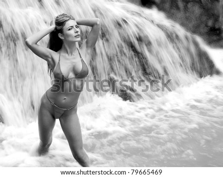 lovely bikini model in rushing tropical waterfall, monochrome