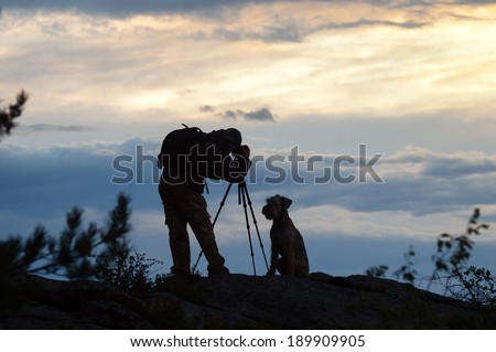 Photographer and dog silhouettes in the mountains at sunset