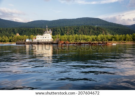 KRASNOYARSK REGION, RUSSIA - JULY 10, 2014: Towboat named Hero Moskvin pulling a barge on the Yenisei River