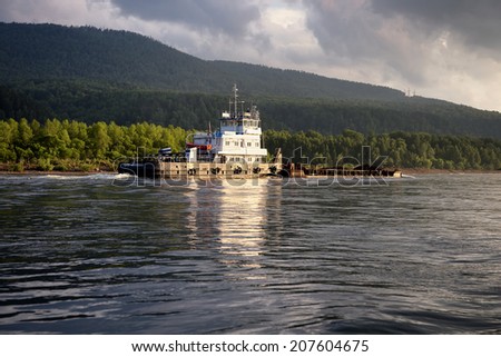 KRASNOYARSK REGION, RUSSIA - JULY 10, 2014: Towboat named Hero Moskvin pulling a barge on the Yenisei River