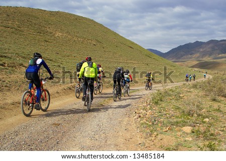 Mountain bikers group racing on rural road in desert